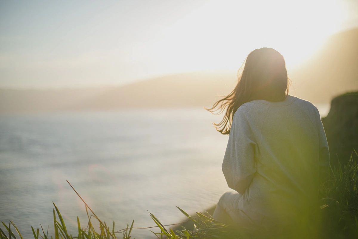 Frau sitzt am Meer und genießt die Auszeit