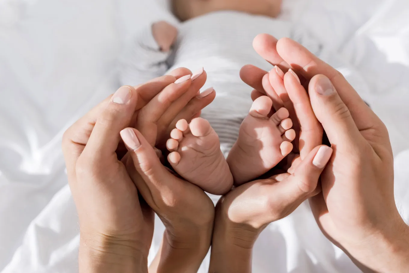 Eltern halten beide Babyfüße in ihren Händen